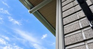 青空を背景にした住宅の外壁タイルと軒下